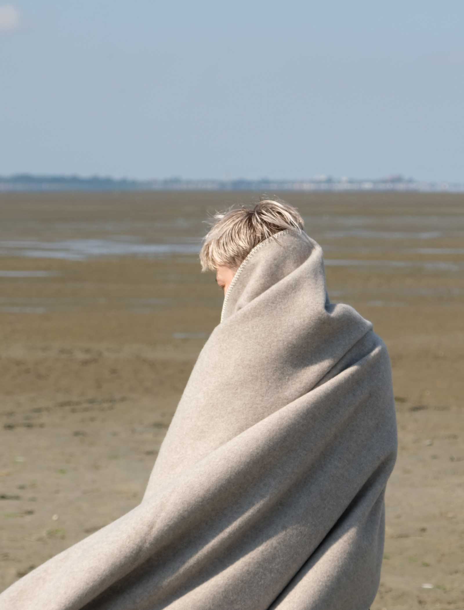 Eingehüllt in einer Wolldecke am Strand